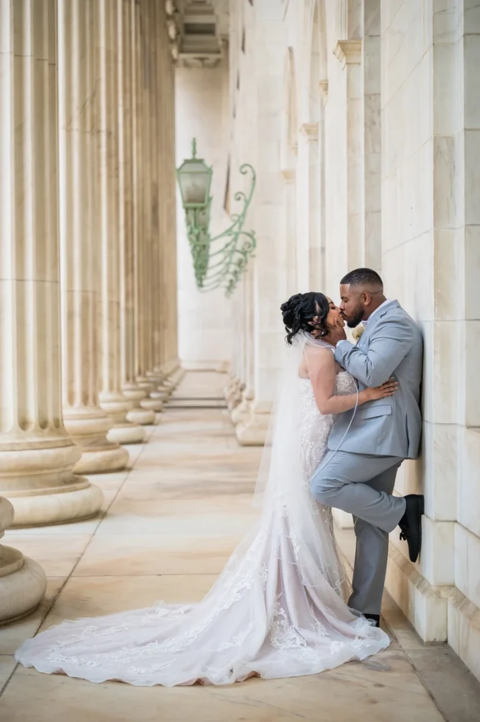 Bride and groom kissing beneath the historic columns of the Denver Federal Courthouse during a Ritz-Carlton Denver wedding